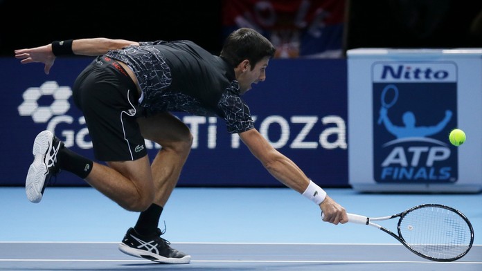 Novak Djokovič odvracia ťažkú loptu od Johna Isnera.