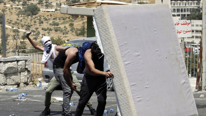 Palestínčania hádžu kamene na izraelskch policajtov.