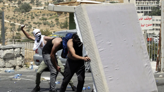 Palestínčania hádžu kamene na izraelskch policajtov.