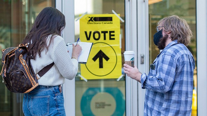 Pracovníčky volebnej komisie stoja pred volebnou miestnosťou.