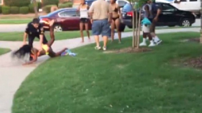 Policajt vykrikuje oplzlé slová voči černošskej mládeži v rasovo zmiešanom dave.