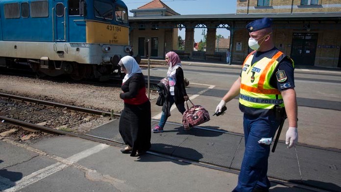 Maďarský policajt eskortuje dve sýrske migrantky k vlaku pred jeho odchodom do utečeneckého tábora na železničnej stanici v maďa