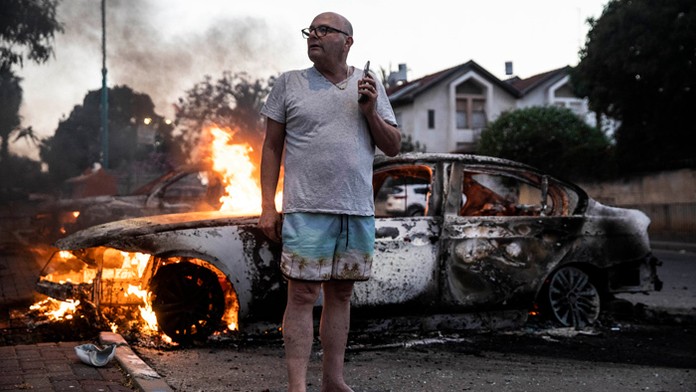 Jacob Simona stojí pri horiacom aute počas potýčok medzi arabskou komunitou a políciou.