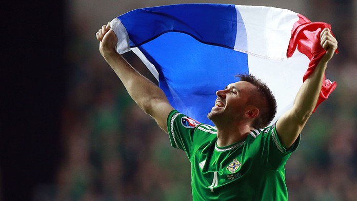 Futbalista Michael O´Neill (Severné Írsko) drží nad hlavou vlajku Francúzska po historicky premiérovom postupe na ME.  
