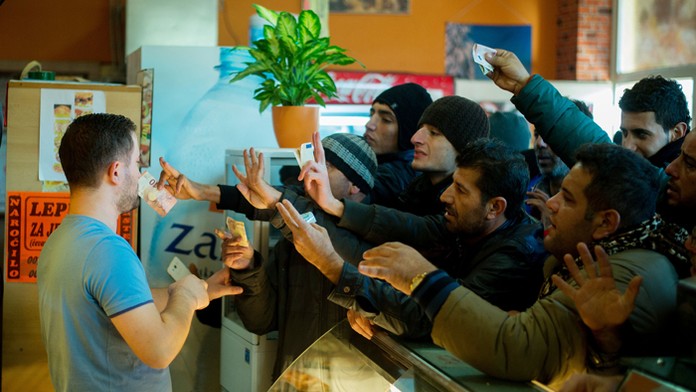 Migranti sa snažia kúpiť niečo v bufete potom ako prekročili rakúsko-slovinskú hranicu v Spielfelde.