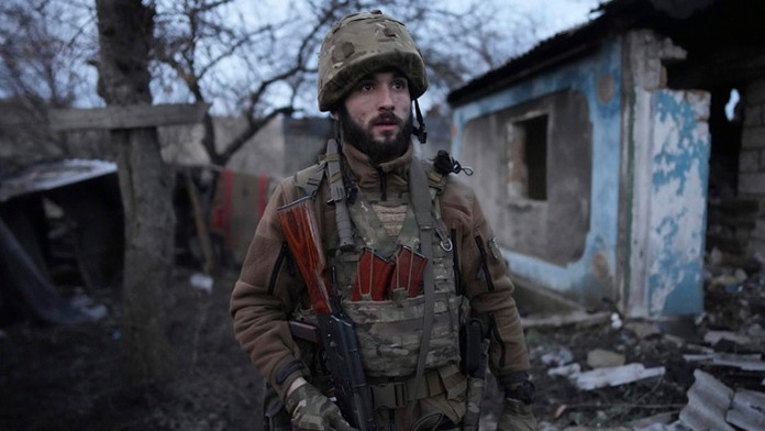 Ukrajinský vojak stojí vo dvore zničeného domu na východe Ukrajiny.