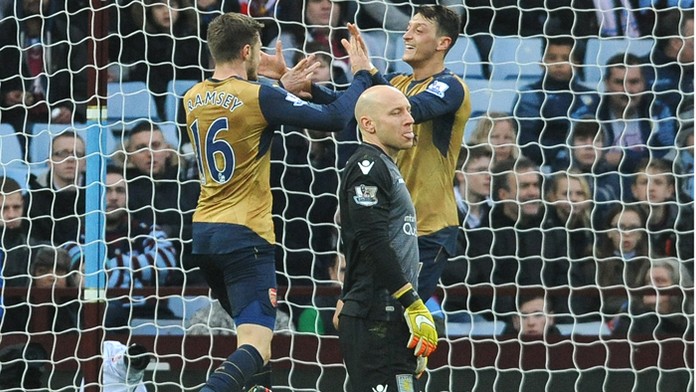 Mesut Özil a Aaron Ramsey (Arsenal) sa tešia po góle proti Aston Villa, v strede jej brankár Brad Guzan.