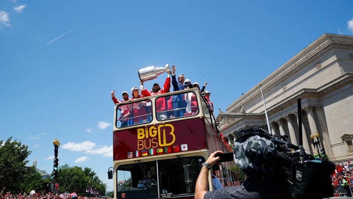 Kapitán Washingtonu Alexander Ovečkin drží nad hlavou Stanleyho pohár počas osláv v uliciach mesta.