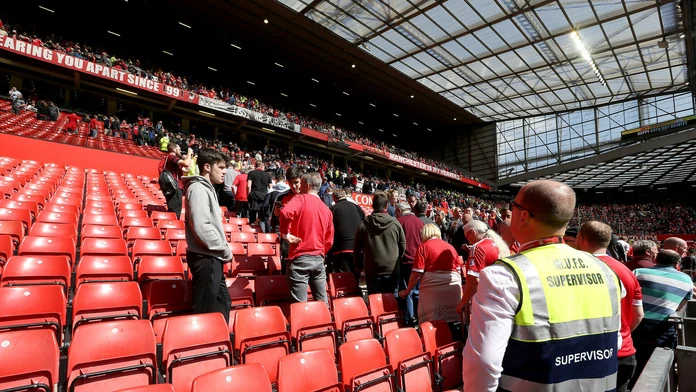 Futbaloví fanúšikovia opúšťajú štadión Old Trafford.