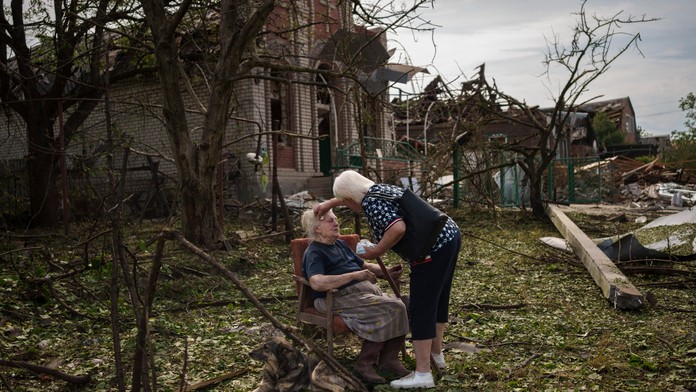 Žena sedí medzi troskami v Družkivke na východe Ukrajiny.