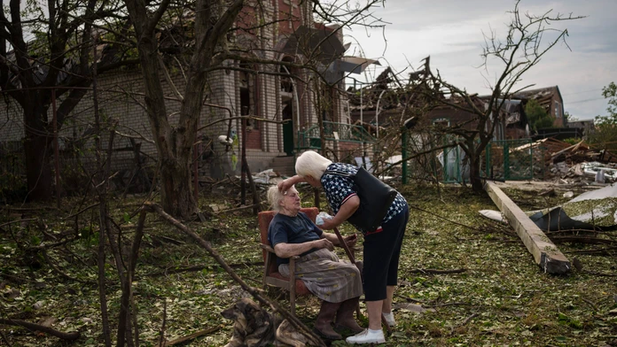 Žena sedí medzi troskami v Družkivke na východe Ukrajiny.