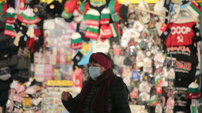 Žena s ochranným rúškom kráča okolo stánku so suvenírmi v centre Sofie.