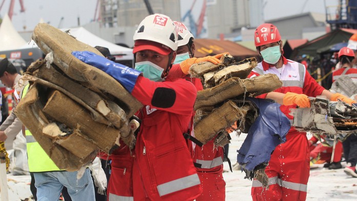 Záchranári odnášajú veci zo zrúteného indonézskeho lietadla.