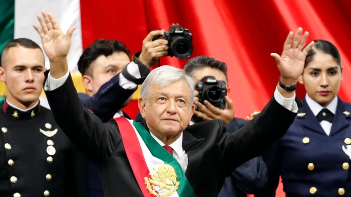 Nový mexický prezident Andrés Manuel López Obrador s prezidentskou stuhou zdraví dav ľudí po jeho prísahe.