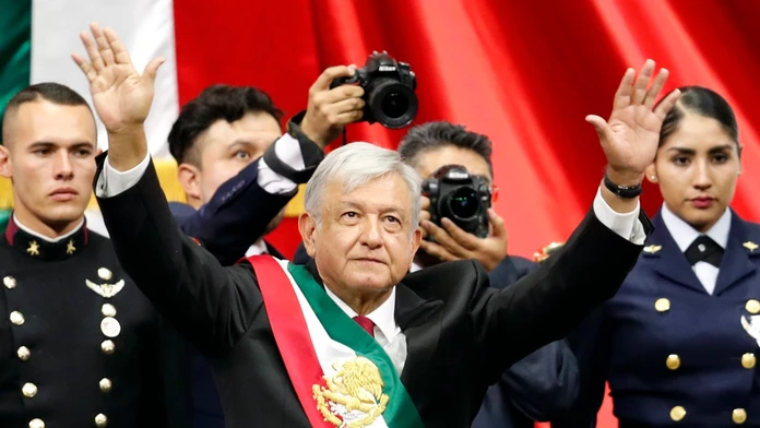 Nový mexický prezident Andrés Manuel López Obrador s prezidentskou stuhou zdraví dav ľudí po jeho prísahe.