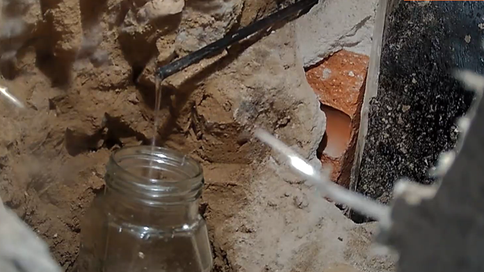 Voda vyteká z hadičky prestrčenej zo susedného domu.