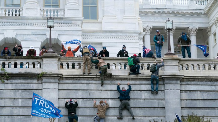 Na snímke stúpenci amerického prezidenta Donalda Trumpa sa vešajú na budovu Kapitolu vo Washingtone.