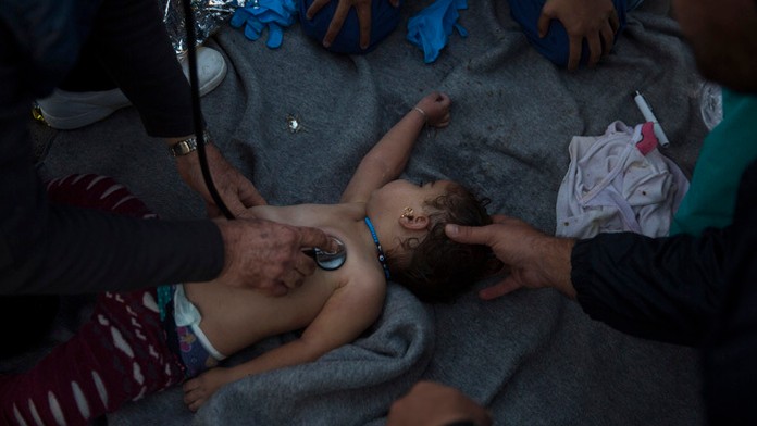 Grécka pobrežná hladka zachraňovala dieťa, ktoré sa nachádzalo na prevrátenej lodi s utečencami.