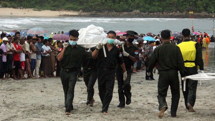 Záchranári nesú telá, ktoré vylovili z vôd rybárskymi plavidlami. 