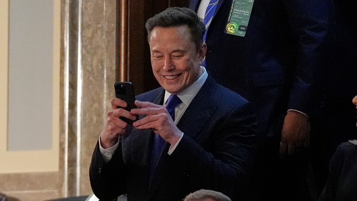 Elon Musk fotí mobilným telefónom pred príhovorom amerického prezidenta Donalda Trumpa.