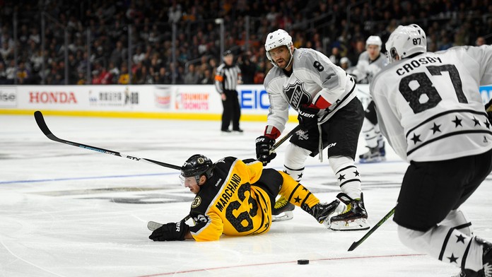 Útočník Atlantickej divízie Brad Marchand leží na ľade po strete s Alexandrom Ovečkinom, Sidney Crosby s pukom (vpravo).