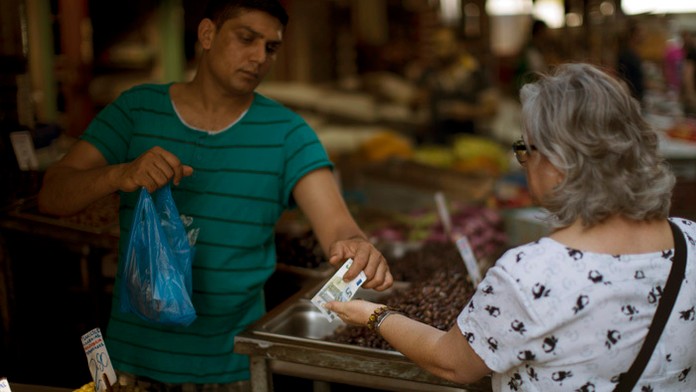 Žena platí na tržnici v Aténach.