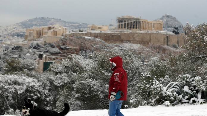 Muž sa prechádza so psom pod Akropolou.