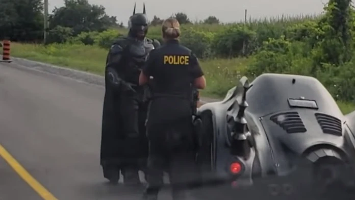 Policajtka kontroluje muža prezlečeného za Batmana.