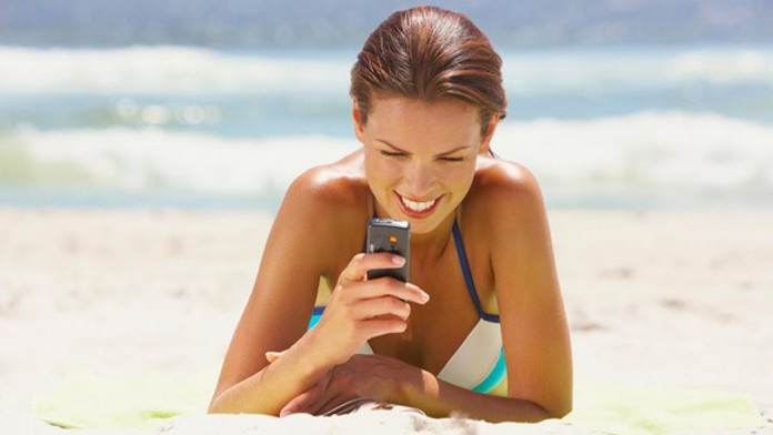 Žena na pláži s mobilom