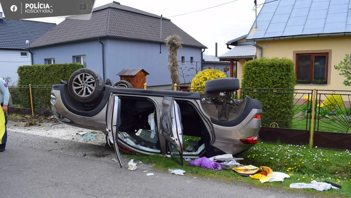 Na snímke je zachytená dopravná nehoda, pri ktorej skončilo auto na streche. V pozadí sú rodinné domy a okolo auta rozhádzané veci, ktoré z neho vypadli.