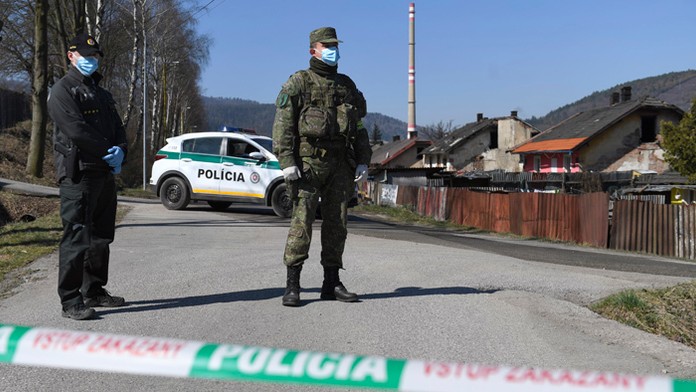 Policajt a vojak strážia uzavretú osadu v Krompachoch.