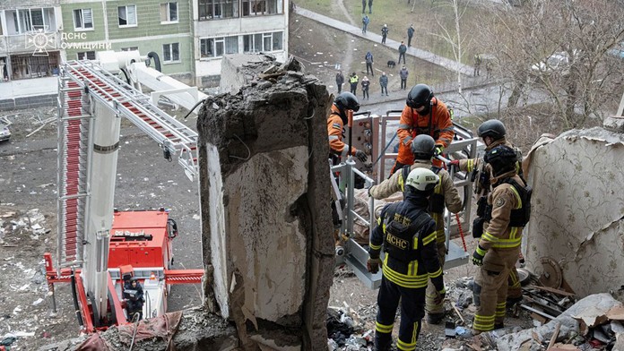 Záchranári prehľadávajú trosky zničenej obytnej budovy po ruskom dronovom útoku v meste Sumy.