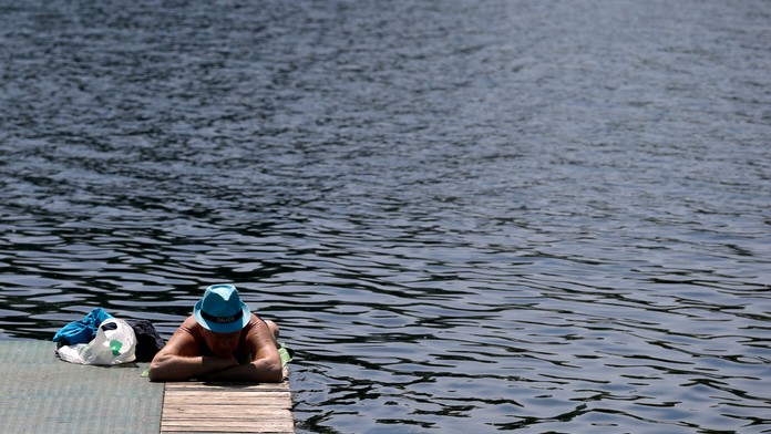 Muž sa opaľuje pri jazere Ada Ciganlija v Belehrade, kde bolo 32 stupňov. 5. mája