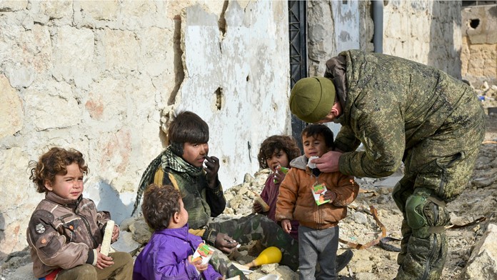 Ruský vojak rozdáva fľaše vodu deťom v Aleppe.