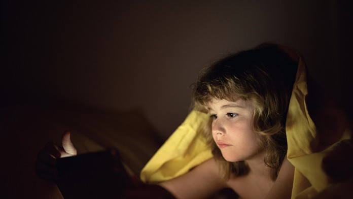 Dieťa na telefóne v posteli.
