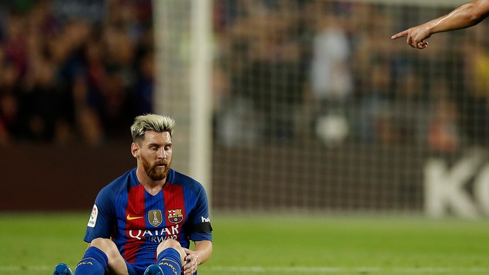 Lionel Messi sedí na trávniku 
