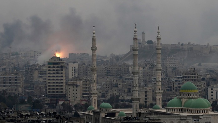 Dym a plamene stúpajú počas leteckých náletov sýrskych vládnych síl na rebelov na východe Aleppa.