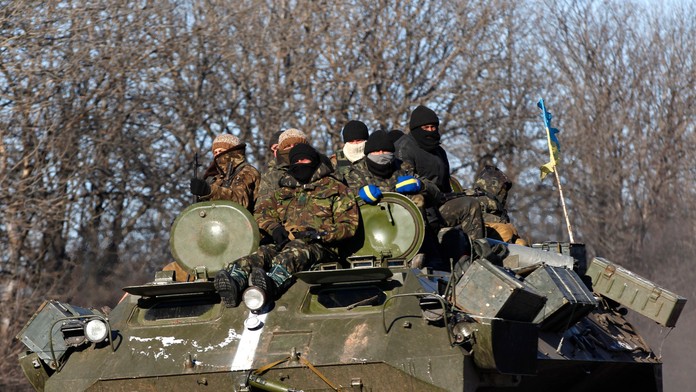 Ukrajinskí vládni vojaci sedia na obrnenom vozidle, ktoré jazdí po ceste von z mesta Artemivsk smerom na Debaľceve 17. februára 