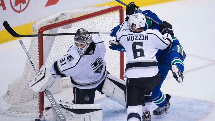 Obranca LA Kings Jake Muzzin sa snaží odstaviť dotiersajúceho Jacka Skilleho pred bránkou Petra Budaja.