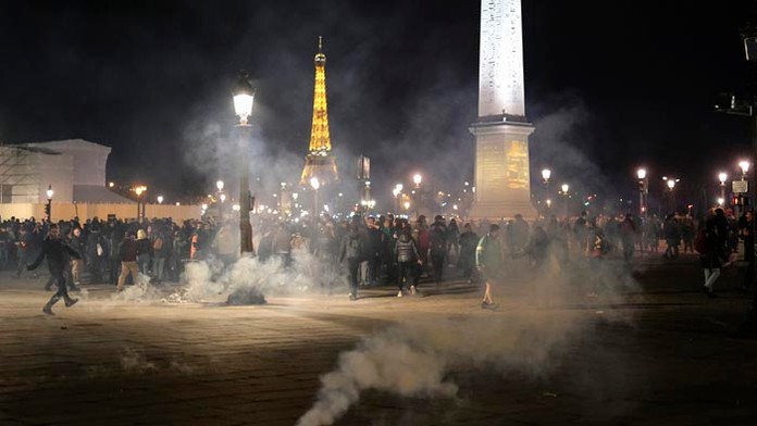 Demonštranti stoja v oblaku slzného plynu po demonštrácii v Paríži.