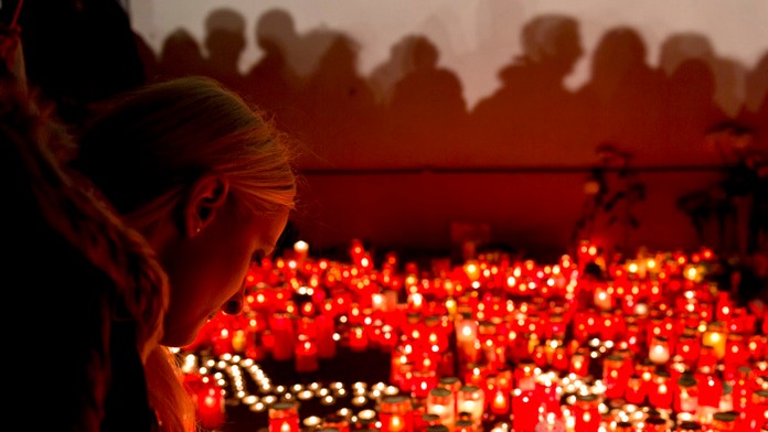 Dievča zapaľuje sviečku na spomienku obetí požiaru v nočnom klube v Bukurešti.