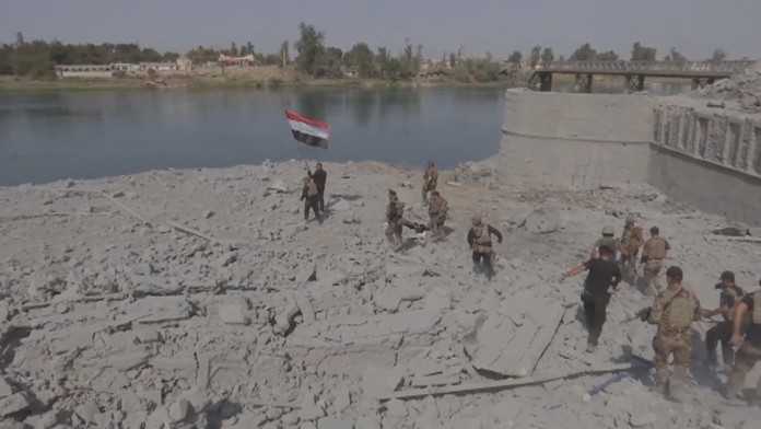 Vojaci vztyčujú irackú zástavu.