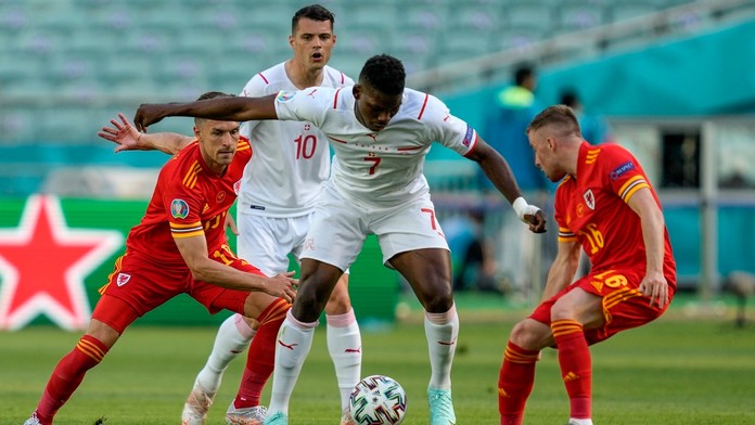 Breel Embolo, v strede, v súboji o loptu s Aaronom Ramseyom a Joeom Moreellom.