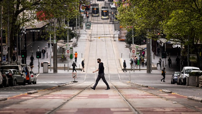 Na archívnej snímke z 30. septembra 2021 ľudia kráčajú cez cestu v Melbourne.