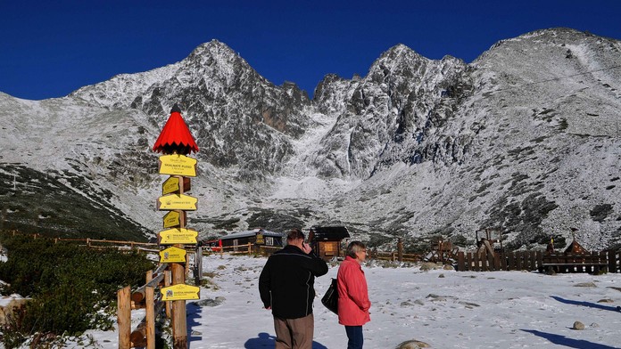 Turisti na zasneženom Skalnatom Plese, v pozadí Lomnický štít vo Vysokých Tatrách 24. septembra 