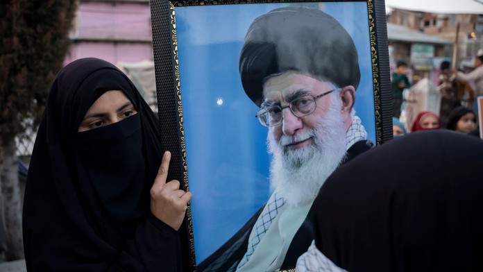 Zahalená obyvateľka Iránu na proteste drží fotografiu Alího Chameního