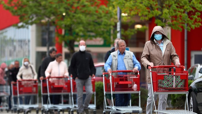 Ľudia s ochrannými rúškami čakajú v rade do záhradníctva v Mníchove 20. apríla 2020.