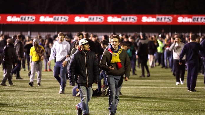 Fanúšikovia sa prechádzajú po trávniku v dueli FA Cupu medzi piatoligovým Suttonom a londýnskym Arsenalom.