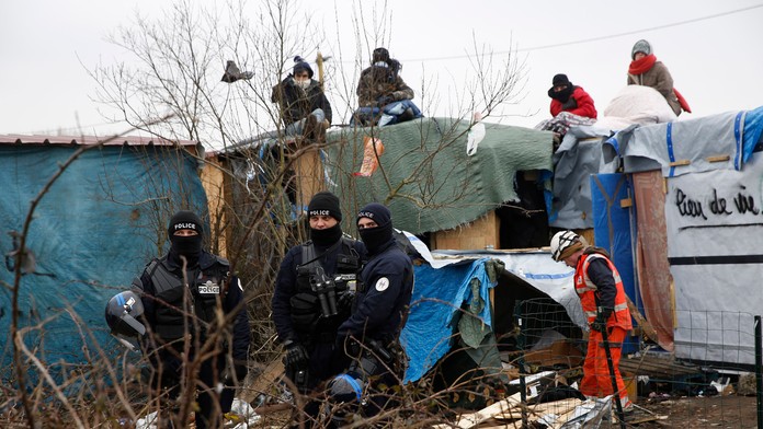 Migranti v tábore pri Calais protestujú na strechách búd.