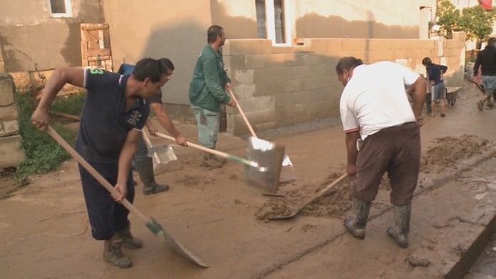 Obyvatelia osady v Rokycanoch čistia cestu po záplave bahna po daždi.